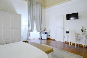 a white bedroom with a bed and a desk at Ada Suites & Spa in Lecce