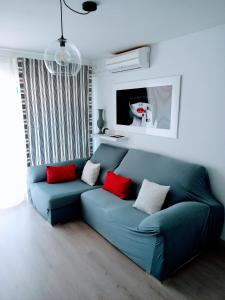 um sofá azul numa sala de estar com almofadas vermelhas em Apartamento El Príncipe em Peníscola