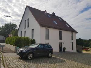 a black car parked in front of a white house at Apartments bei Playmobil EG,130m2 in Zirndorf