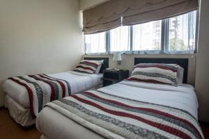 two beds in a room with a window at Hotel Capelli Express in Talca