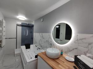 a white bathroom with a sink and a mirror at Groom Epernay - Jacuzzi & Champagne in Épernay