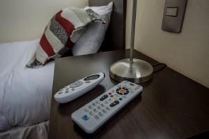 dos controles remotos sentados en una mesa junto a una cama en Hotel Capelli Express, en Talca