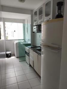 uma cozinha com electrodomésticos brancos e uma grande janela em Apartamento Condominio Caminho dos Ventos em Aracaju