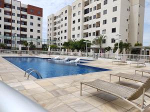 uma piscina com espreguiçadeiras e edifícios em Apartamento Condominio Caminho dos Ventos em Aracaju
