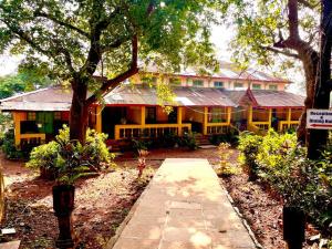 a large yellow house with a tree in front of it at The Byke Retreat - Laxmi Resort - Pan India Pure Veg Hotel Chain in Matheran