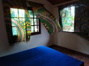 Cette chambre dispose de deux fenêtres avec des rideaux colorés. dans l'établissement Casa de Praia Picinguaba, à Ubatuba
