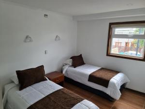 1 dormitorio con 2 camas y ventana en Alto Balmaceda, en Puerto Natales