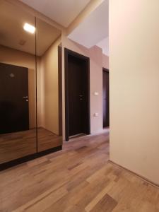 Kopaonik Lux Apartman في كوباونيك: غرفة فارغة مع مرآة وأرضيات خشبية