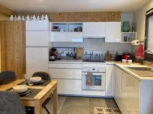 a kitchen with white cabinets and a wooden table at Résidence Le Faber in Le Grand-Bornand