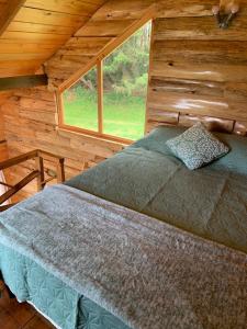 a bed in a log cabin with a window at Charming cabin surrounded by nature in El Escudero