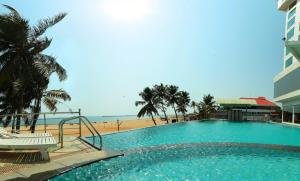 a large swimming pool next to a beach at The Quilon Beach Hotel and Convention Center in Kollam