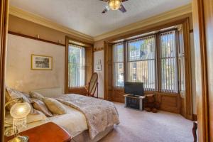 a bedroom with a bed and a tv and windows at The Old Bank House Self Catering Apartment Dornoch in Dornoch