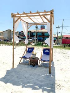 duas cadeiras e uma mesa na praia em PIER BEACH CLUB em Cabo Frio
