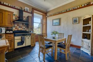 uma cozinha com uma mesa, cadeiras e um fogão em The Old Bank House Self Catering Apartment Dornoch em Dornoch