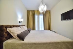 - une chambre avec un grand lit et un lustre dans l'établissement Apartman Kalina, à Zlatibor
