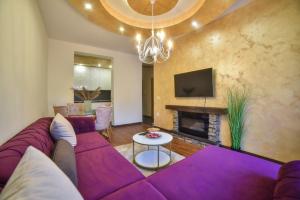 un salon avec un canapé violet et une cheminée dans l'établissement Apartman Kalina, à Zlatibor