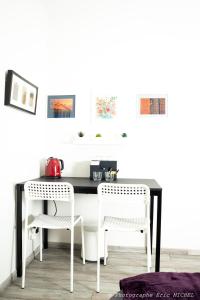 a black and white kitchen table with two white chairs at 1 chambre 14 m2 + SDB + cuisine + Terrasse en jardin pour 2 voyageurs in Trévignin