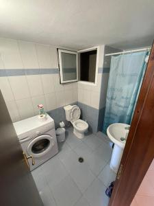a bathroom with a toilet a sink and a washing machine at L.T. Apartment 5th street in Sarandë