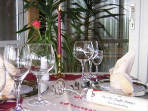 vier Weingläser auf einem Tisch mit einer Kerze in der Unterkunft Hotel & Freizeitpark Am Lärchenberg in Schirgiswalde