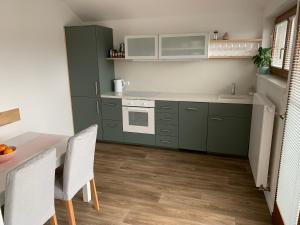 een keuken met groene kasten en een tafel en stoelen bij Residence Sarka Top in Praag