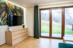 a living room with a tv and sliding glass doors at Apartament na Wzgórzu 3, Sauny, ebike, las, widok - 5D Apartamenty in Świeradów-Zdrój