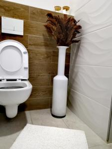 a white vase with a plant in a bathroom at Sandev Apartments Kolorit in Štip +21 photos
