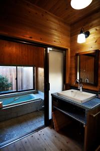 a bathroom with a bath tub and a sink at 隠れや古民家の宿 えんや 天然温泉露天風呂付きの貸別荘 in Nasu