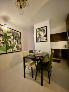 ein Esszimmer mit einem Tisch, Stühlen und Gemälden in der Unterkunft Sandev Apartments in Štip