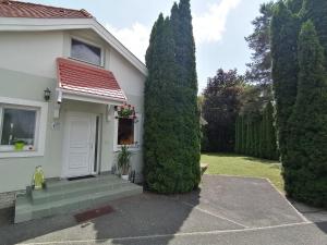 Biały dom z białymi drzwiami i dwoma drzewami w obiekcie Relax Apartman Bükfürdő w Bukfurdo