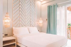 a bedroom with a white bed and chandeliers at MUNI MUNI VILLAS SIARGAO in General Luna