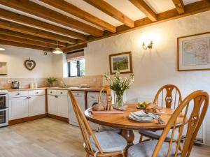 een keuken met een houten tafel en stoelen bij Bramble Cottage in Bigbury