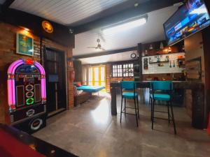 een bar met een tafel en stoelen en een videospel bij Bangalô das Lagartixas ,casa stúdio com piscina aquecida privativa a 20 minutos do Centro de Curitiba in Colombo