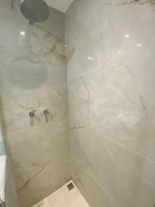 baño con ducha de mármol blanco en Apartment Ipanema Arpoador - 300m da praia, en Río de Janeiro