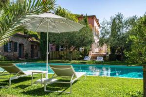 un par de sillas y una sombrilla junto a la piscina en Gites de la Villa Pergola en Salernes
