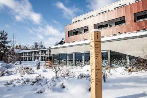 a wooden ruler in the snow in front of a building at Amenity Hotel & Resort Lipno in Lipno nad Vltavou