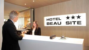 a man and a woman standing at a hotel reception counter at Hôtel Beau Site in Lourdes