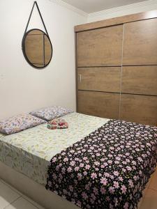 a bedroom with a bed and a dresser with flowers on it at Apartamento aconchegante 1 quadra da praia in Praia Grande