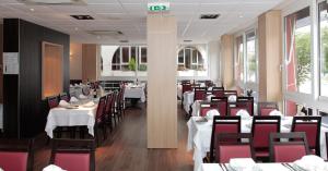 ルルドにあるHôtel Beau Siteのダイニングルーム(白いテーブル、赤い椅子付)