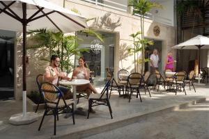 a woman sitting at a table with an umbrella at Casa Marina Beach & Reef All Inclusive in Sosúa