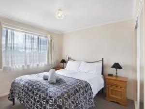 a white bedroom with a bed and a window at Beloka 7 Free WiFi in Jindabyne