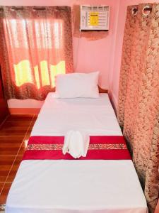 a small room with two beds with a towel on it at JayDin Travellers Inn in Panglao