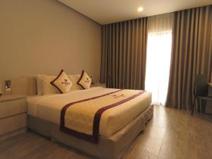 sypialnia z łóżkiem z poduszkami i oknem w obiekcie VISUHA HOTEL w mieście Hà Tiên