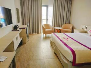 una habitación de hotel con una cama grande y sillas en VISUHA HOTEL, en Hà Tiên