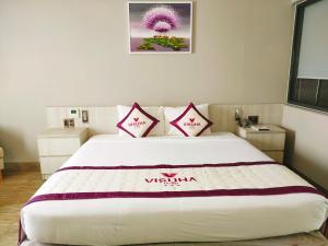 una camera da letto con un grande letto bianco con due cuscini di VISUHA HOTEL a Hà Tiên