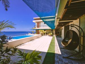 a house with a swimming pool next to the ocean at Miami Heat Beach Resort powered by Cocotel in Morong