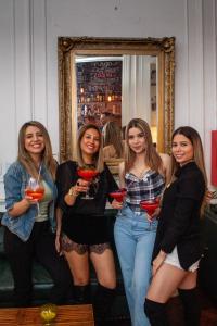 un grupo de mujeres sosteniendo vasos de martini delante de un espejo en IDEAL SOCIAL Hostel en Buenos Aires