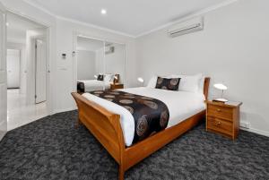 a bedroom with a large bed with a wooden frame at Fawkner Executive Suites & Serviced Apartments in Melbourne