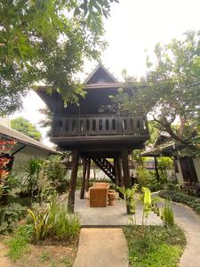 a house with a black roof in a garden at Na Mantra Resort in Chiang Mai
