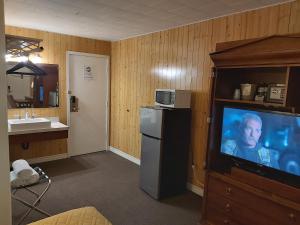 een kamer met een televisie en een badkamer met een wastafel bij Travel Inn Hearst in Hearst