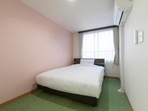 um quarto com uma cama branca e uma janela em Tabist Hotel Miyakonojo Miyazaki em Miyakonojō